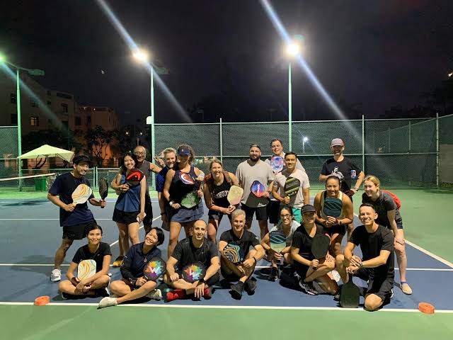 Foreign visitors and Vietnamese players posing together after a pickleball game