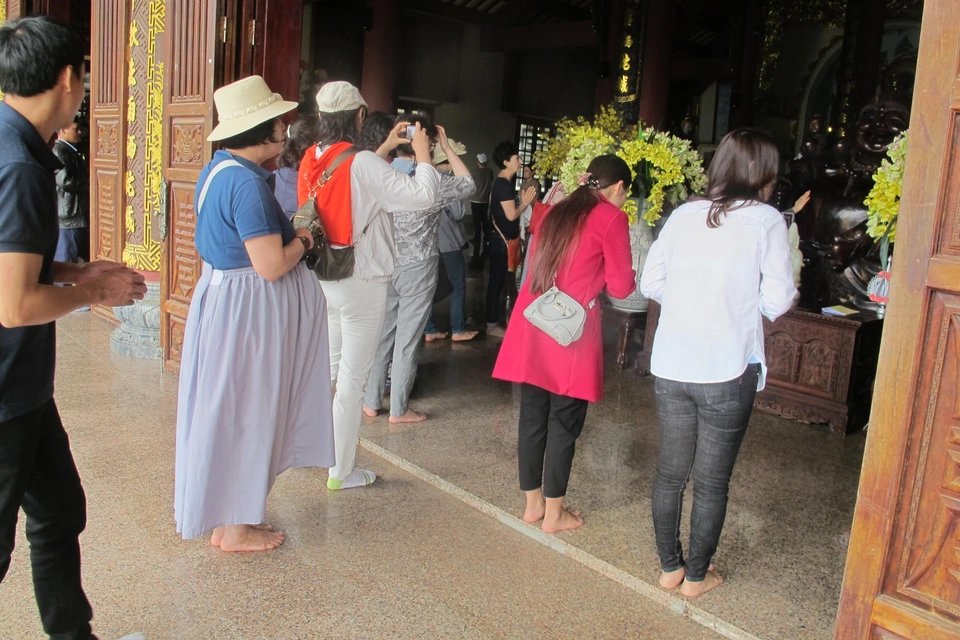 A woman with a scarf over her shoulders visiting a pagoda in Vietnam