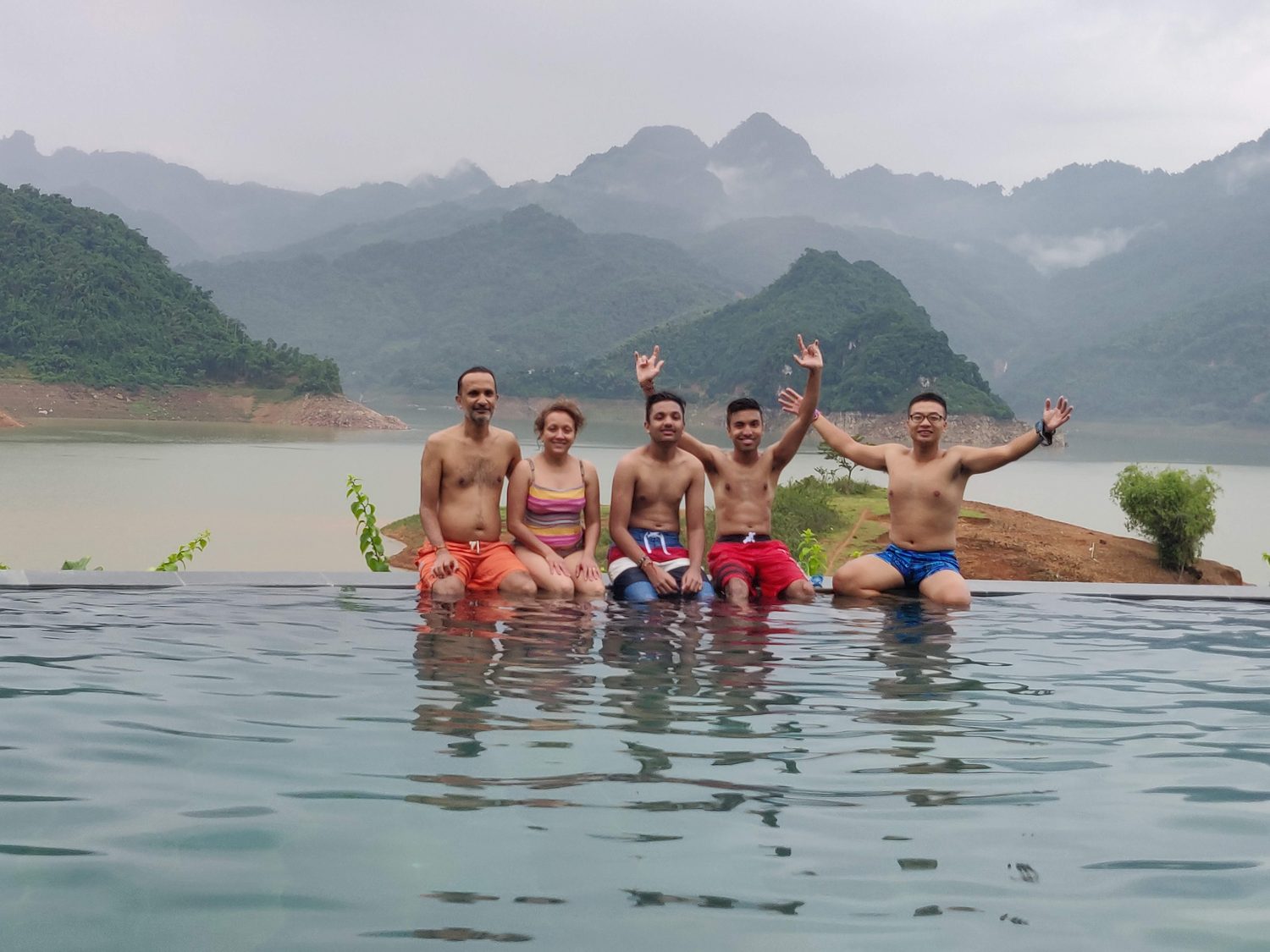 Friends in an infinity pool looking out at limestone mountains