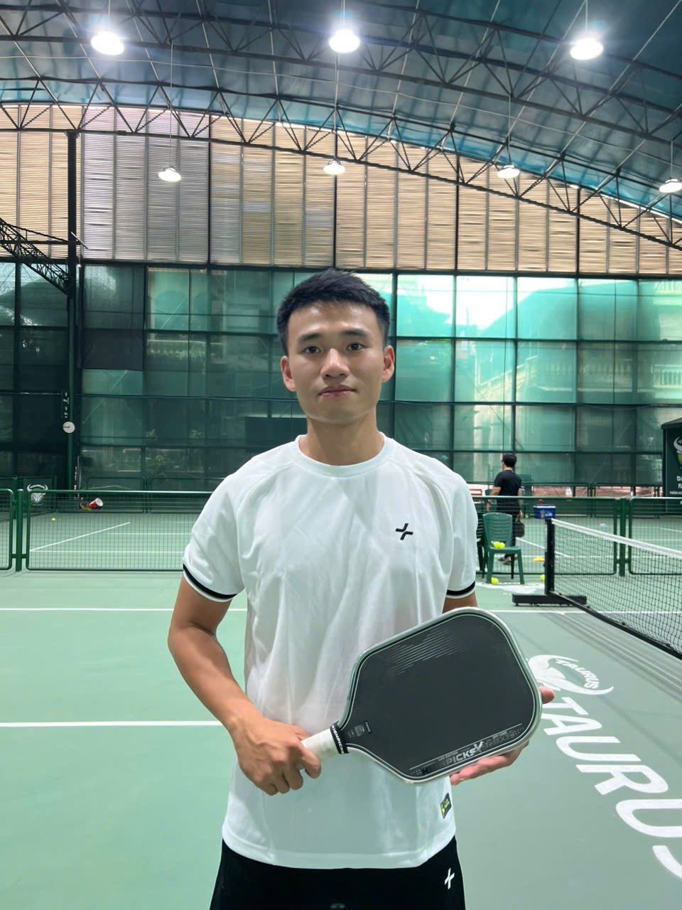 Hoang, one of our tour guides, holding a paddle on court at Taurus, Hanoi