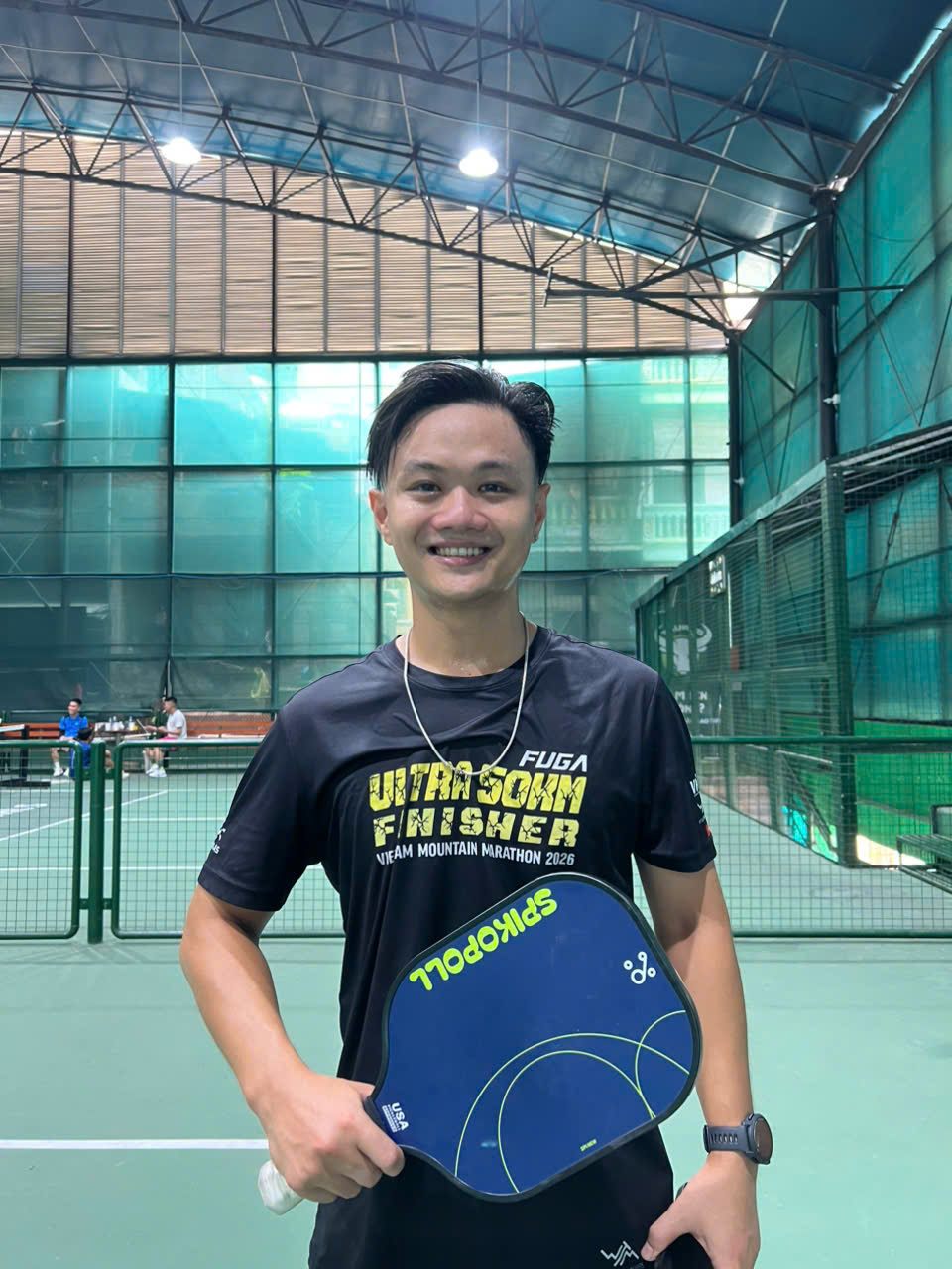 Long, one of our tour guides, smiling with a blue paddle at Taurus, Hanoi