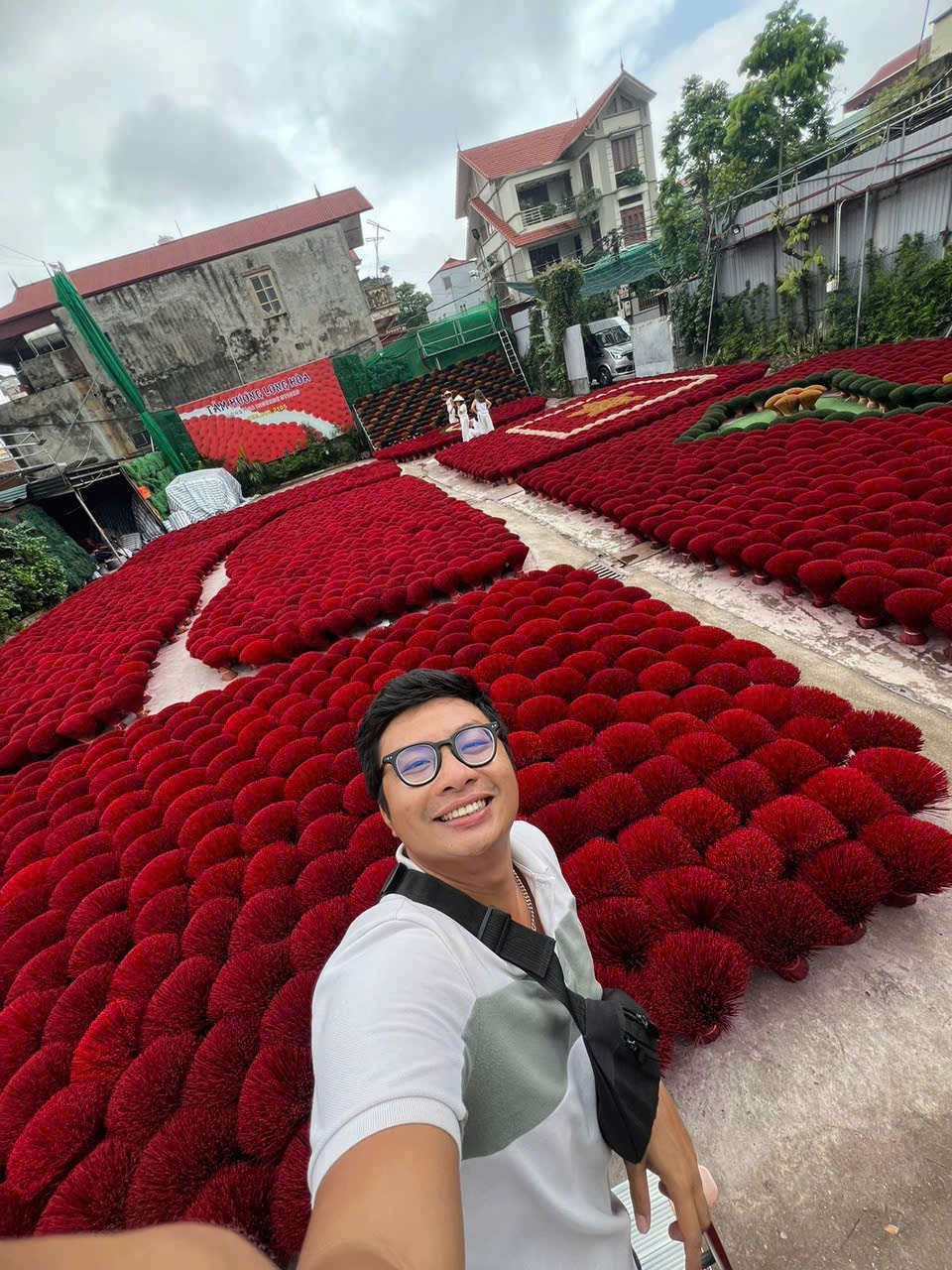 Kevin among bundles of red incense drying in Quang Phu Cau village