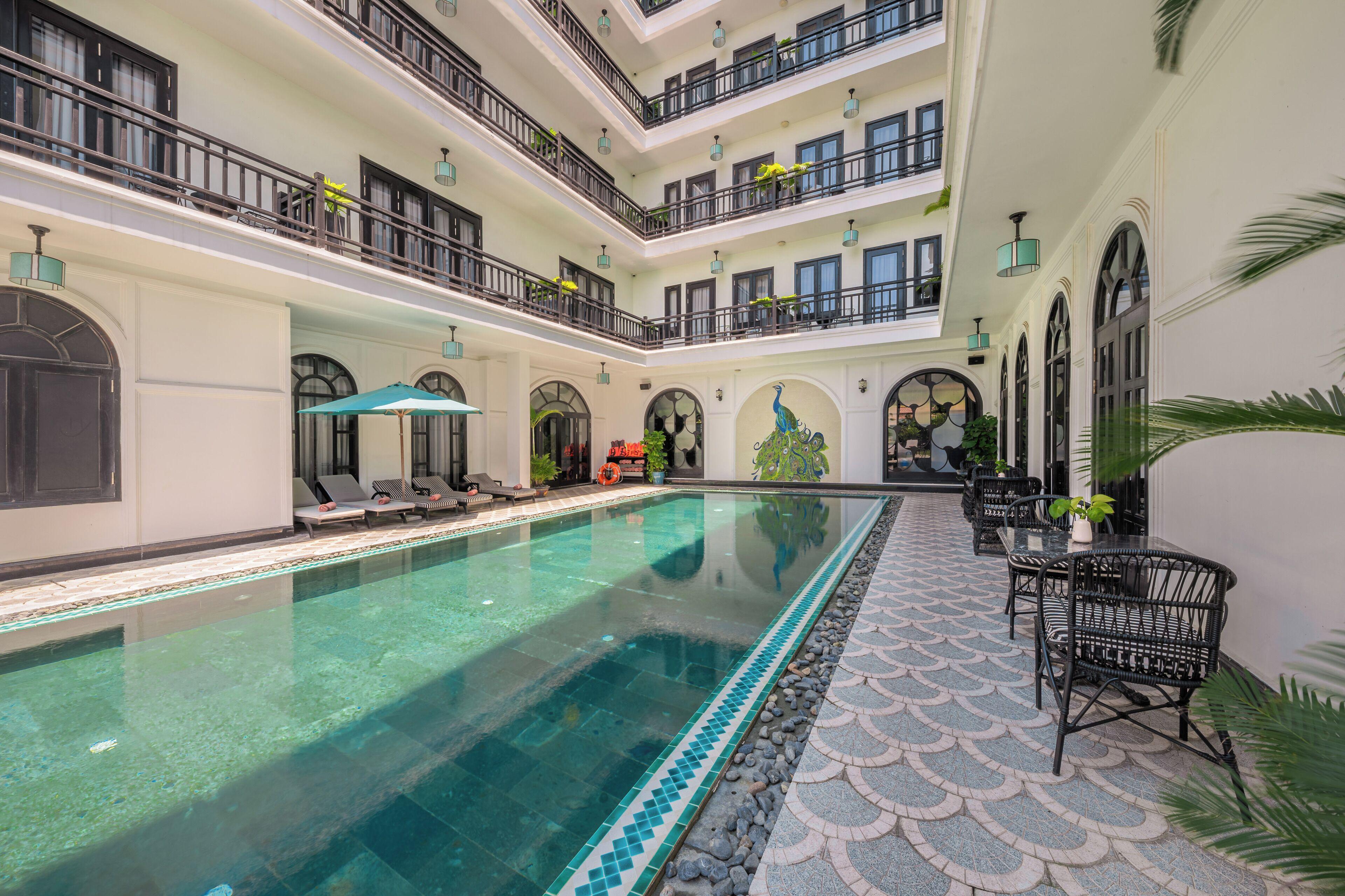 A swimming pool surrounded by tropical garden at a hotel in Hoi An
