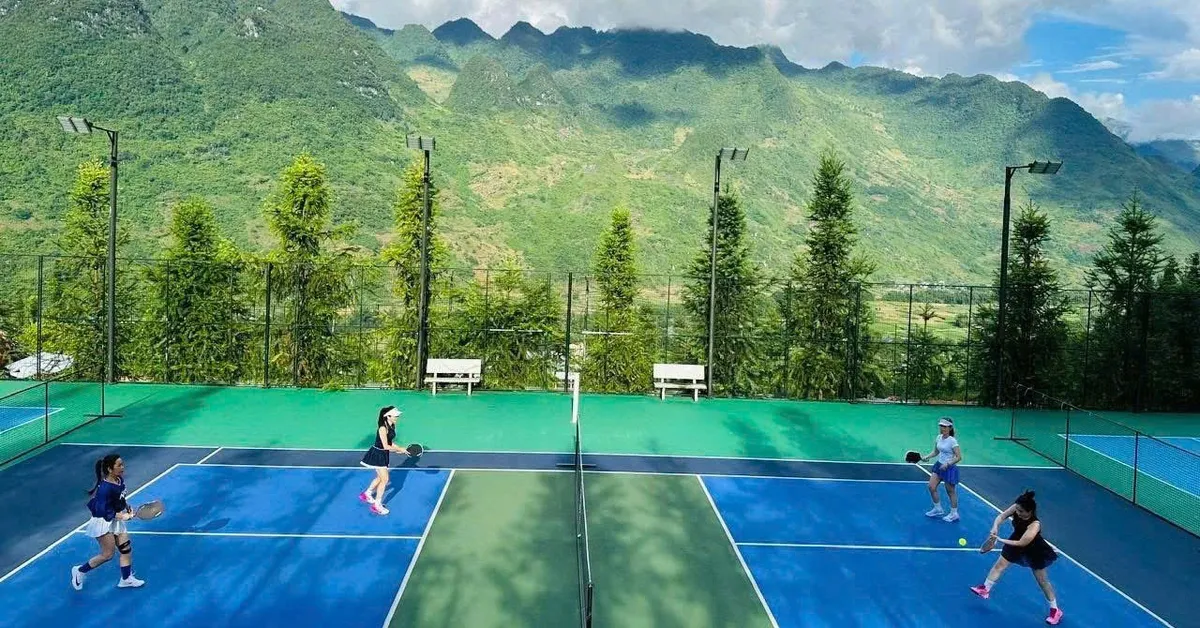 Four players on a pickleball court with green limestone mountains behind them in Ha Giang, northern Vietnam
